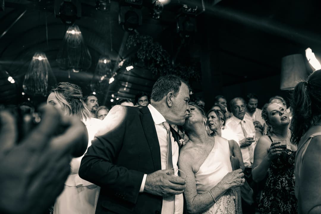 a couple kissing while walking out of a limousine while holding some drinks
